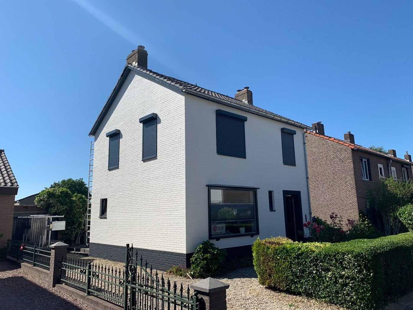 Handbediende rolluiken in donkergrijs, geplaatst op een moderne woning met witte gevel in Sittard.