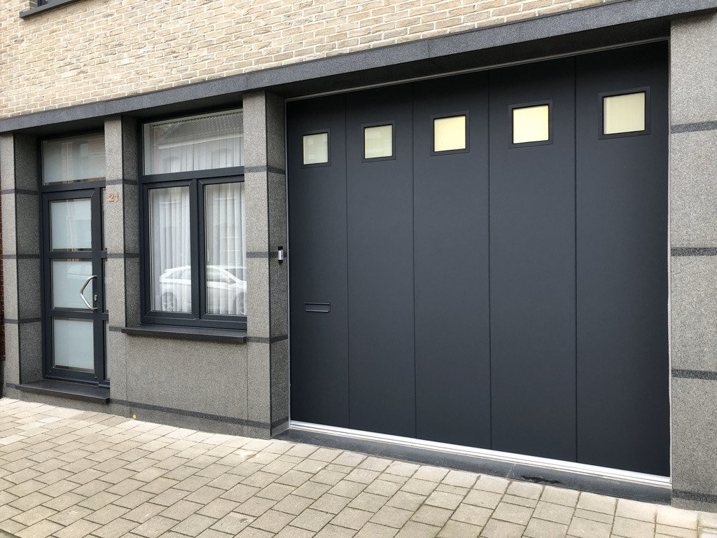 Moderne sectionaaldeur met glasvensters in een grijze gevel.