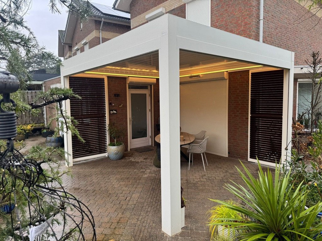 Moderne witte veranda aan huis met lamellendak en ledverlichting.