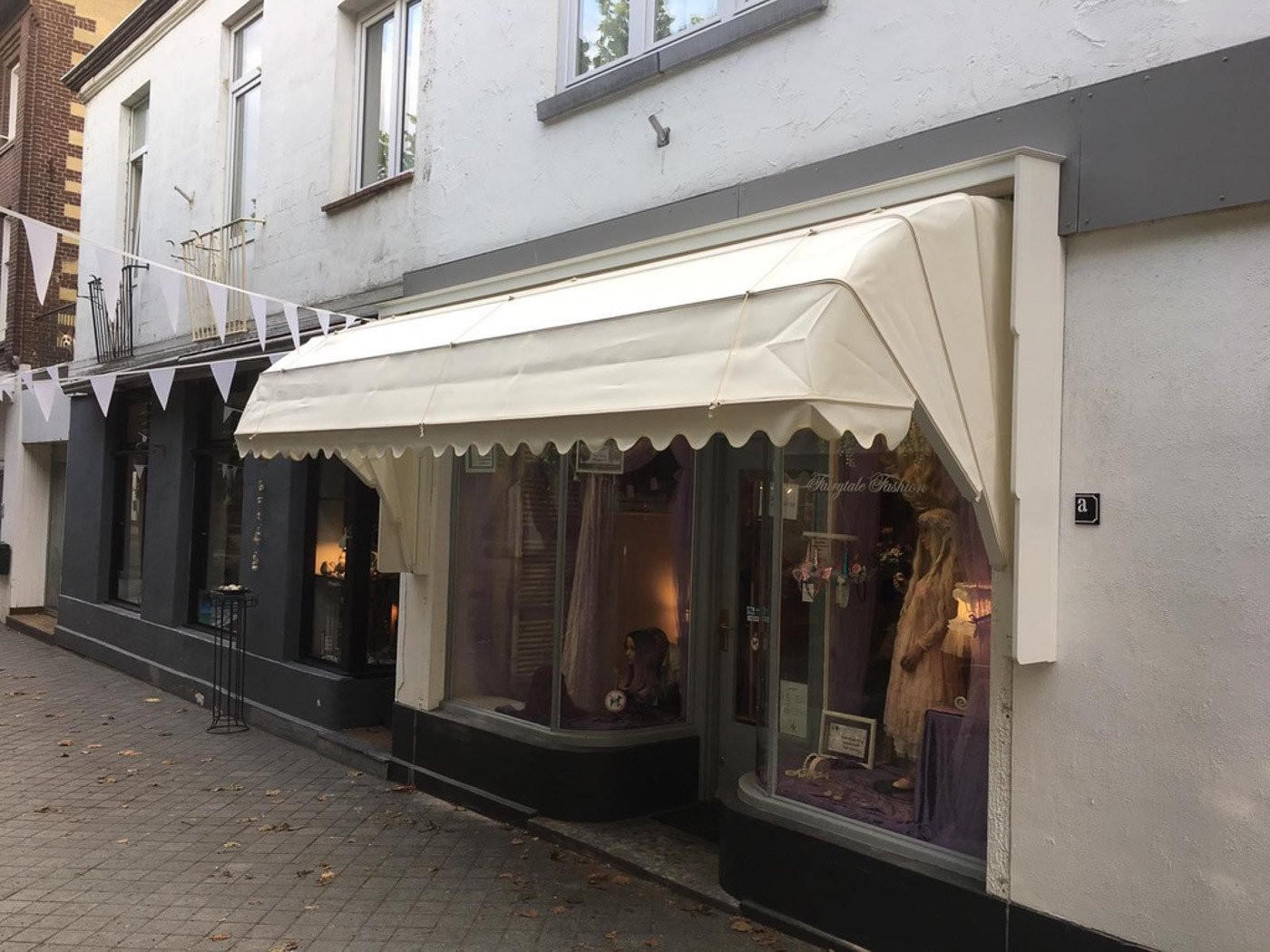 Elegante markies bij een winkel met een lichtbeige kleur en sierlijk afgewerkte randen.