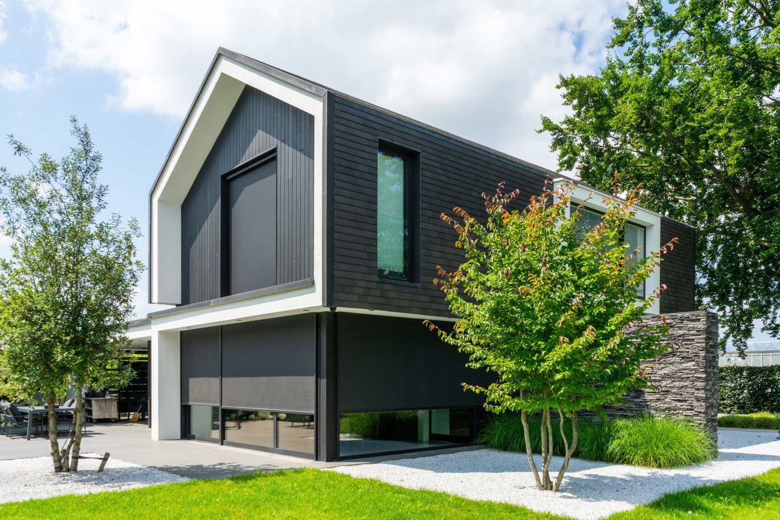 Luxueuze vrijstaande woning met zwarte screens voor privacy en zonwering.