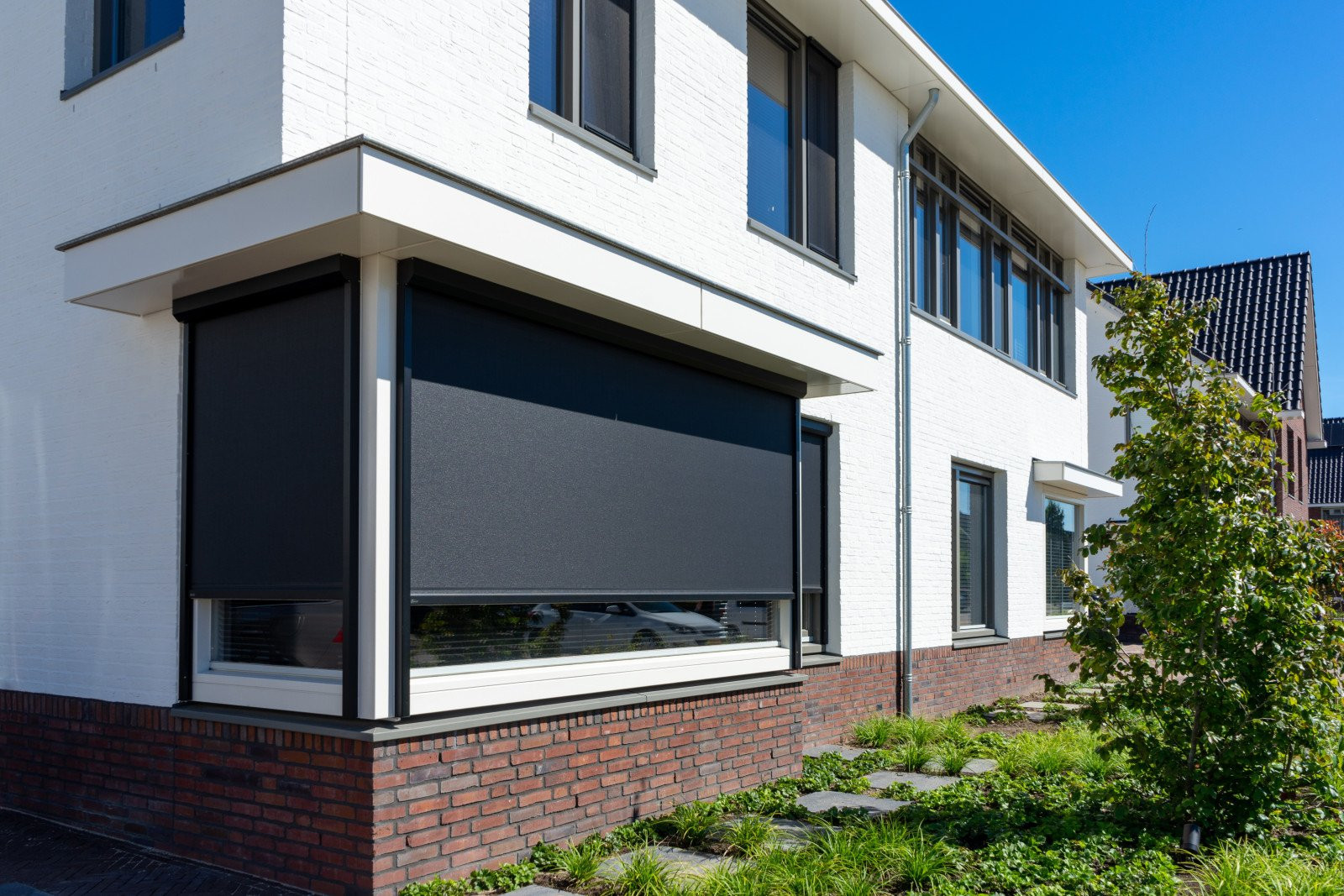 Moderne ritzscreens in zwart voor een strakke woning, zorgen voor schaduw en privacy.