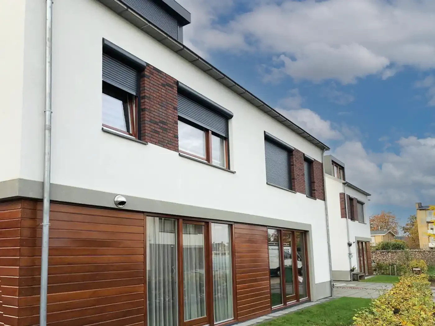 Handbediende rolluiken in een moderne woning met houten en witte gevel.