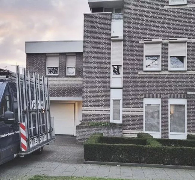 View of a home with electric roller shutters and a garage, surrounded by a tidy garden in Limburg.