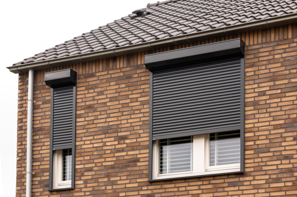 Zwarte elektrische rolluiken op bovenverdieping woning in Limburg.