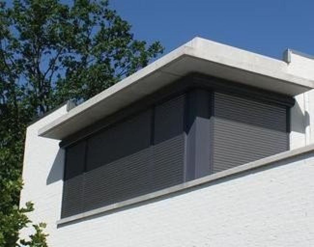 Modern-style manually operated roller shutters on a building with a white fa&ccedil;ade.