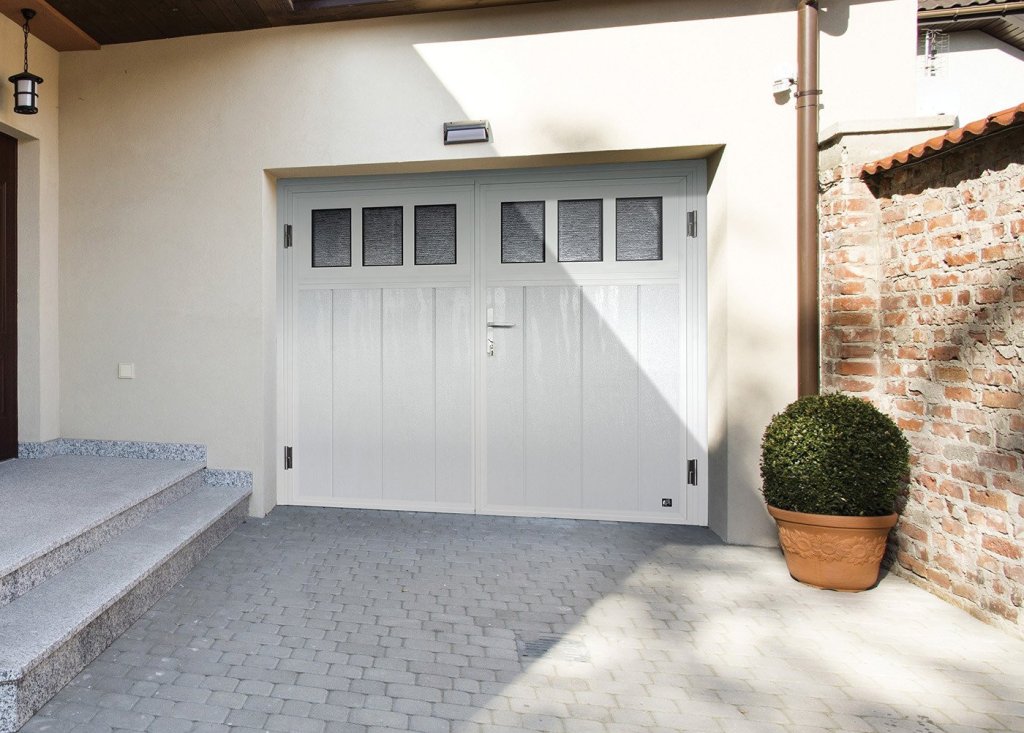 Elegante openslaande garagepoorten voor jouw huis in Sittard. Openslaande garagedeuren in een moderne garage, met groene plantenbak op een stenen vloer.