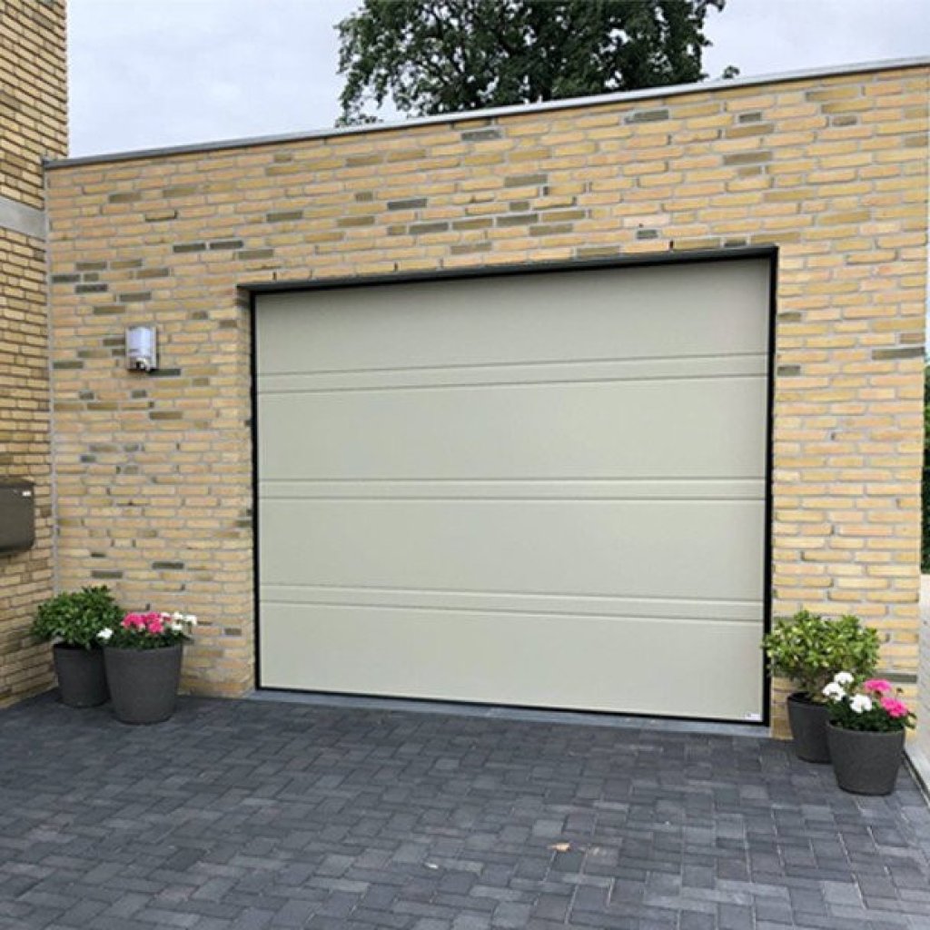Strakke sectionaalpoort in een lichte kleur met moderne uitstraling, omlijst door een stenen wand en bloempotten.