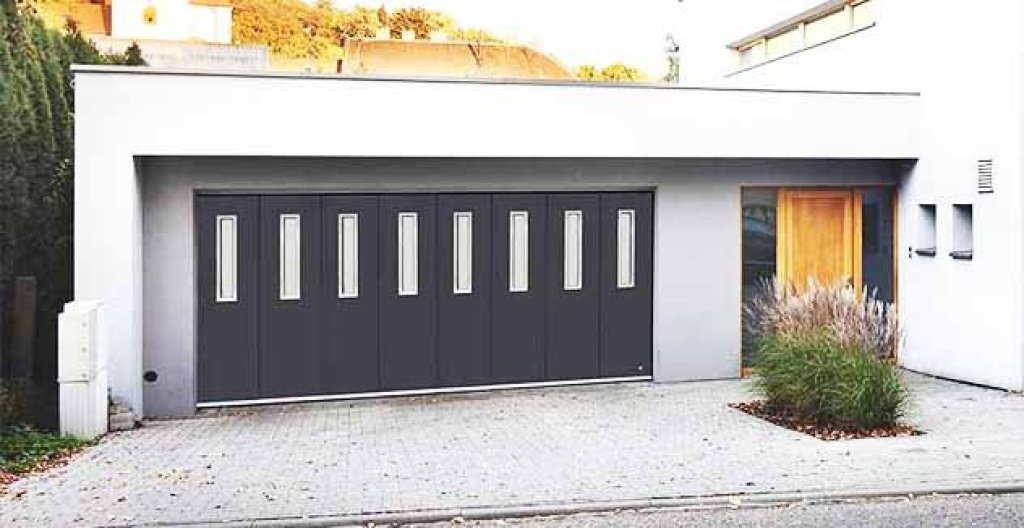 Moderne zijwaartse sectionaaldeur in een eigentijdse garage met verticale glazen zichtvensters.