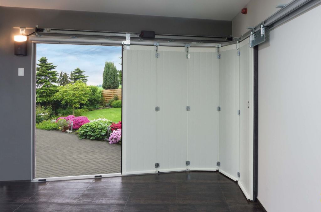 Elegant side-sliding sectional door with a modern finish, opened onto a green garden full of flowers.