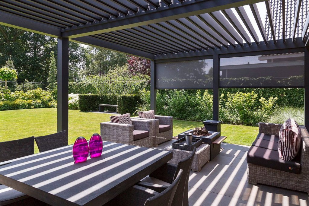 Lamellendak op uw overkapping? Renoco monteert in Sittard - Geleen en Limburg!. Modern lamellendak terrasoverkapping met comfortabele zithoek en tuinzicht in Sittard-Geleen.