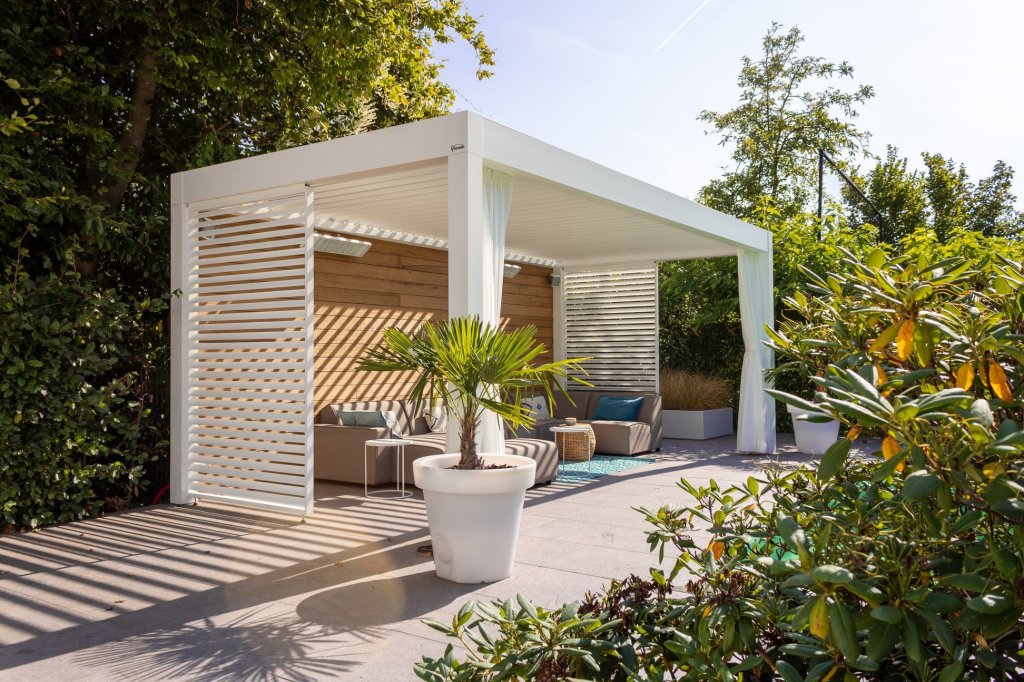 Modern terrasoverkapping met lamellendak met loungeset en schutters tegen de zon.