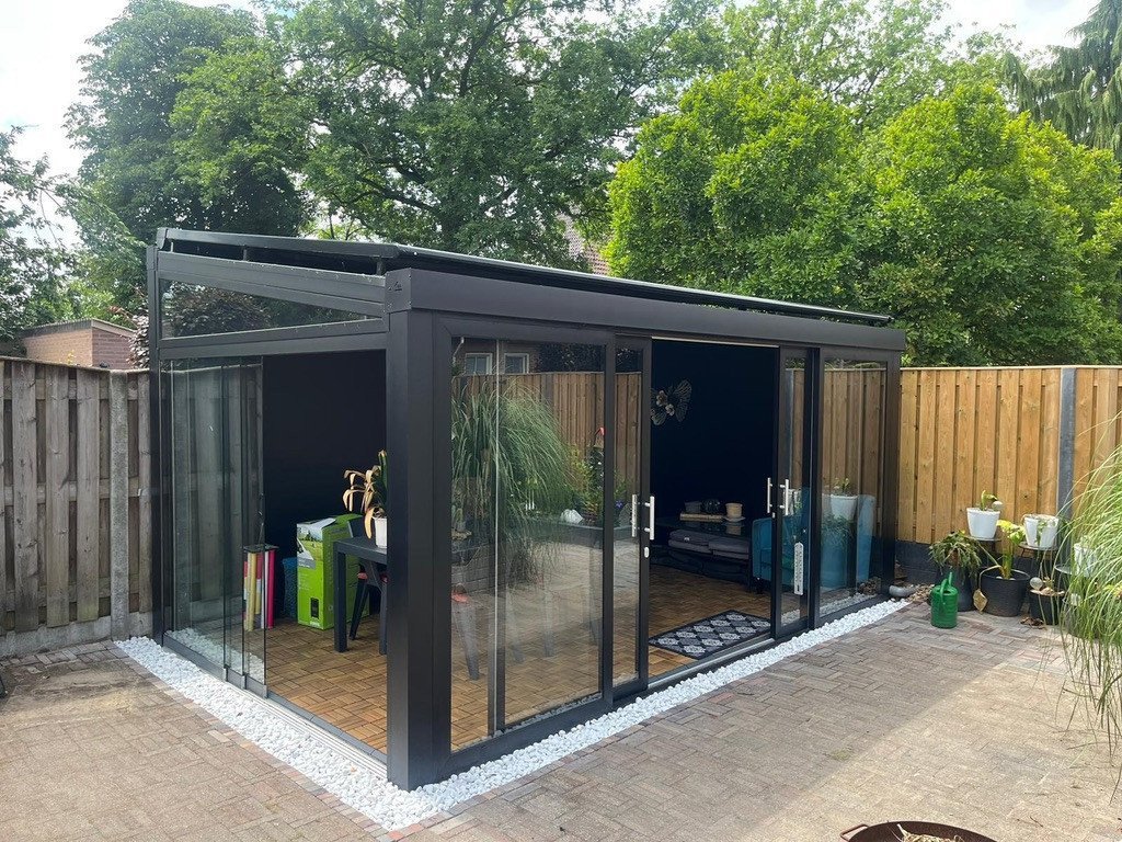 Moderne vrijstaande luxe terrasoverkapping met glazen schuifwanden, met tuinmeubelen.