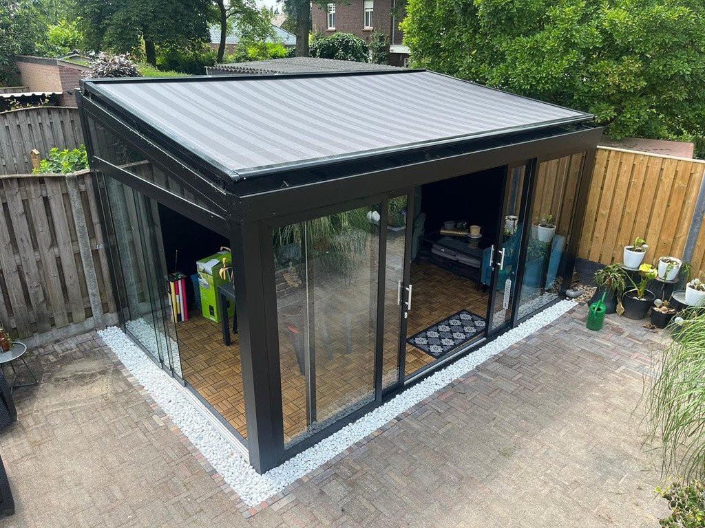 Vrijstaande overkapping met glazen wanden en dak afgewerkt met veranda zonwering.