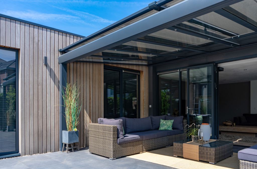 Luxe glazen terrasoverkapping met verandazonwering met moderne loungeset.