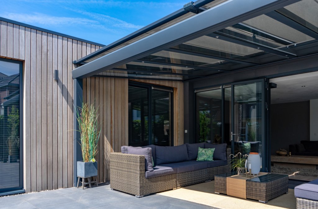 Luxe glazen terrasoverkapping met verandazonwering met moderne loungeset.