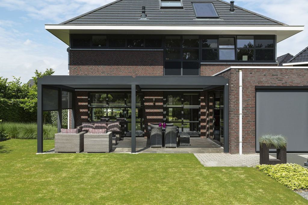 Stilvolle Veranda am Haus mit bequemen Gartenm&ouml;beln, ausgestattet mit Screens und Terrassendach-Beschattung.