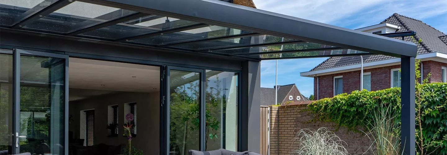 Moderne terrasoverkapping aan huis met glazen dak voorzien van verandazonwering.