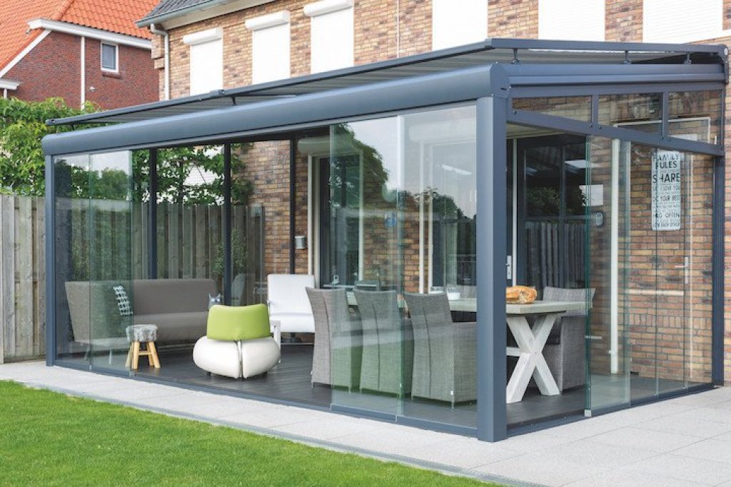 Moderne veranda  aan huis met glazen wanden en stijlvolle tuinmeubelen, afgewerkt met veranda zonwering.