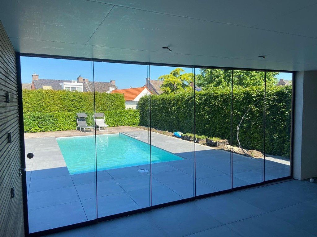 Glasschiebewand mit Blick auf einen modernen Pool und einen sauber eingez&auml;unten Garten in Sittard-Geleen, Limburg.