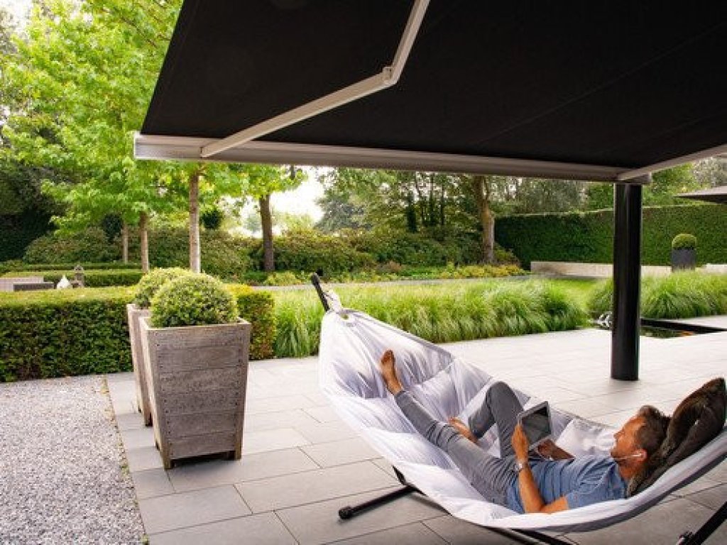 Geniet van de schaduw met een Knikarmscherm van Renoco. Knikarmscherm in een moderne tuin, biedt schaduw voor een ontspannen moment op het terras.