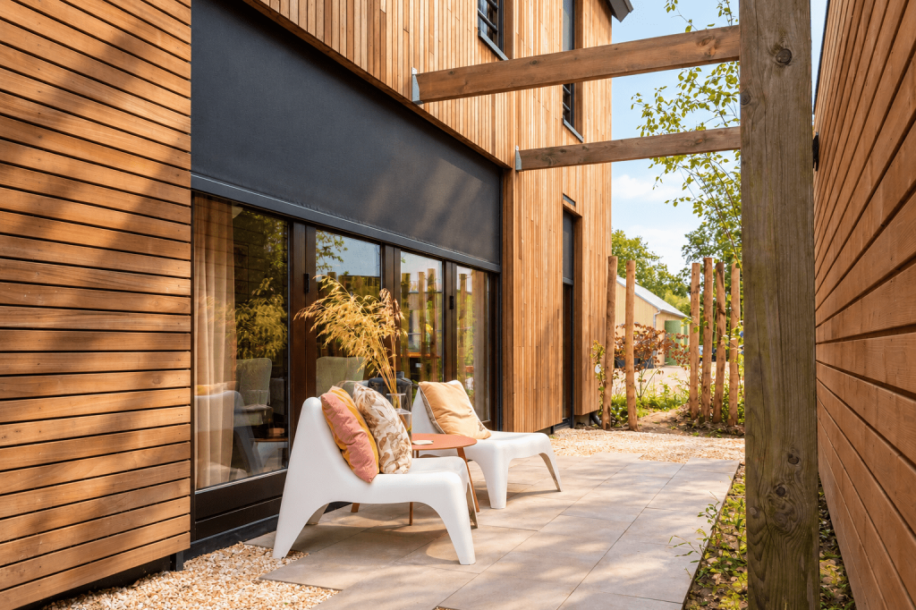 Moderne woning met houten gevel en donker screen als buitenzonwering.
