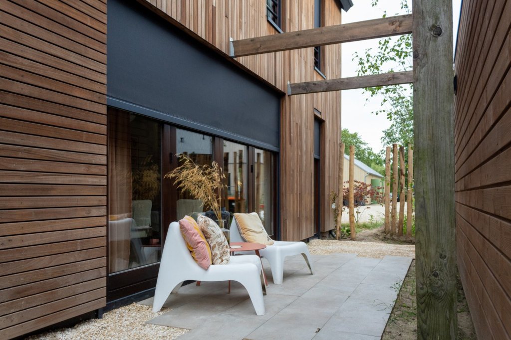 Luxe ritzscreen voor zonwering naast design terrasmeubels op tuinterras.