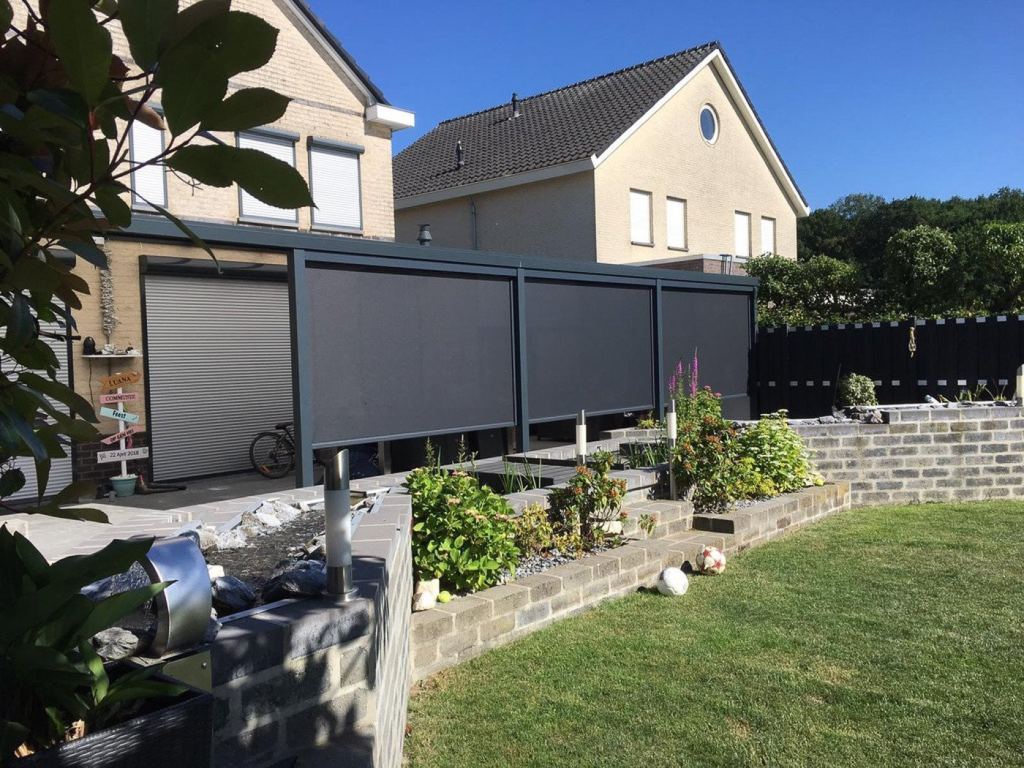Modern screens providing sun shading and privacy in a neat garden setting, with green plants and a stone garden wall.