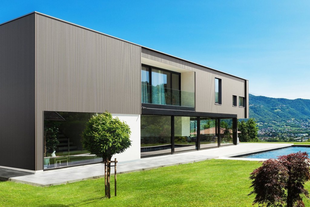 Composiet gevelbekleding WEO. Moderne gevelbekleding in een strakke, eigentijdse stijl voor een woning met grote ramen en een zwembad.