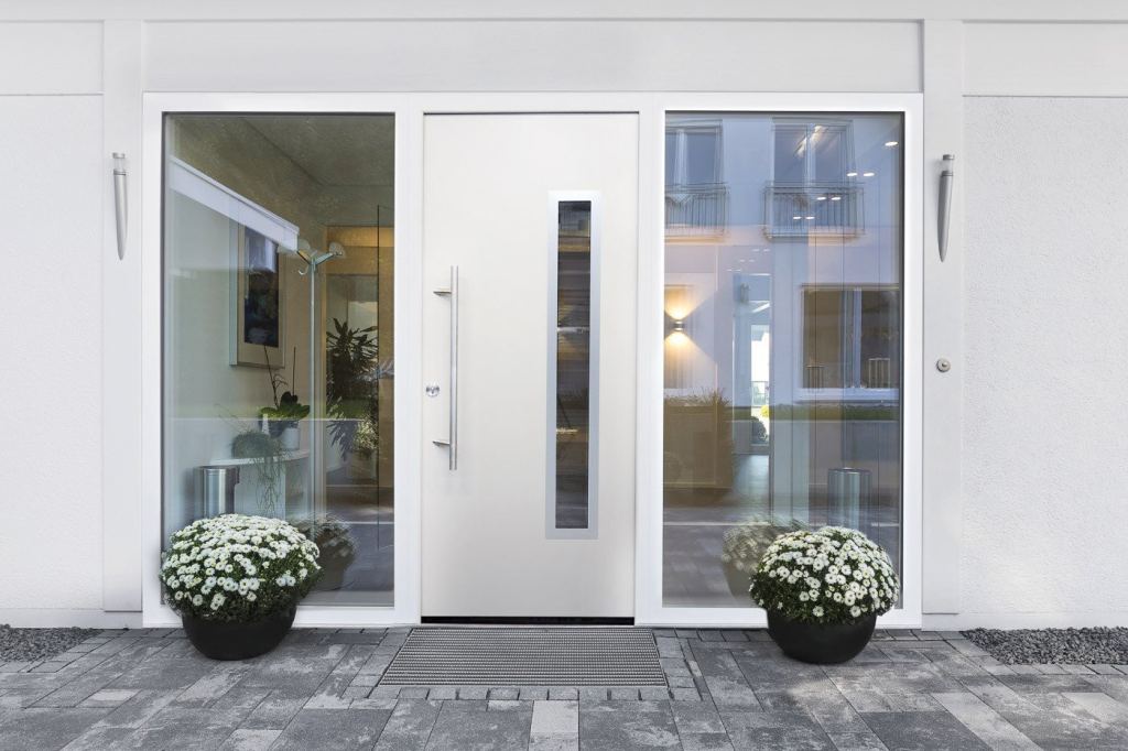 Sleek, modern white front door with glass panels and a silver handle, the doorstep dressed with flower pots.