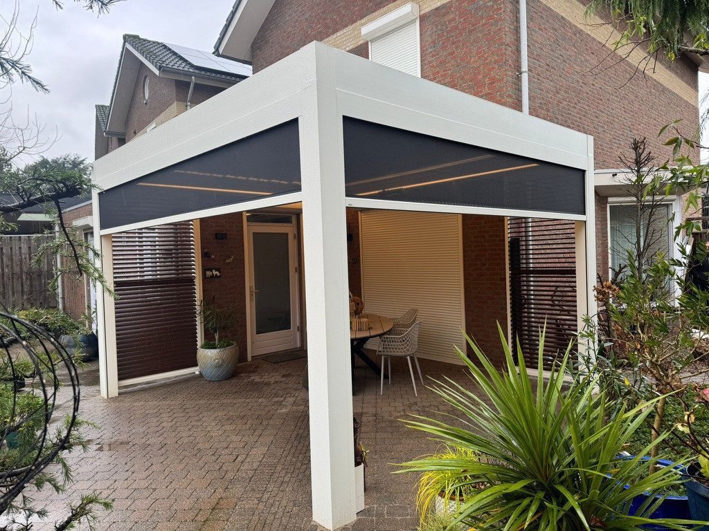 Heerlijk genieten van uw eigen lamellendak? Renoco monteert in Sittard - Geleen en Limburg!. Moderne witte terrasoverkapping aan huis met screens en schutters, dit is een veranda met alle luxe afgewerkt.