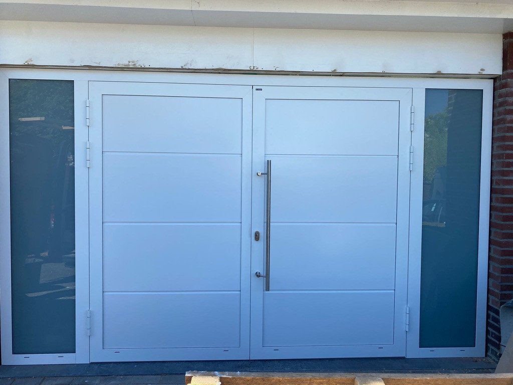 Witte openslaande witte garagedeuren in Sittard-Geleen én Limburg. Openslaande witte garagedeuren met glazen panelen in Sittard-Geleen én Limburg.