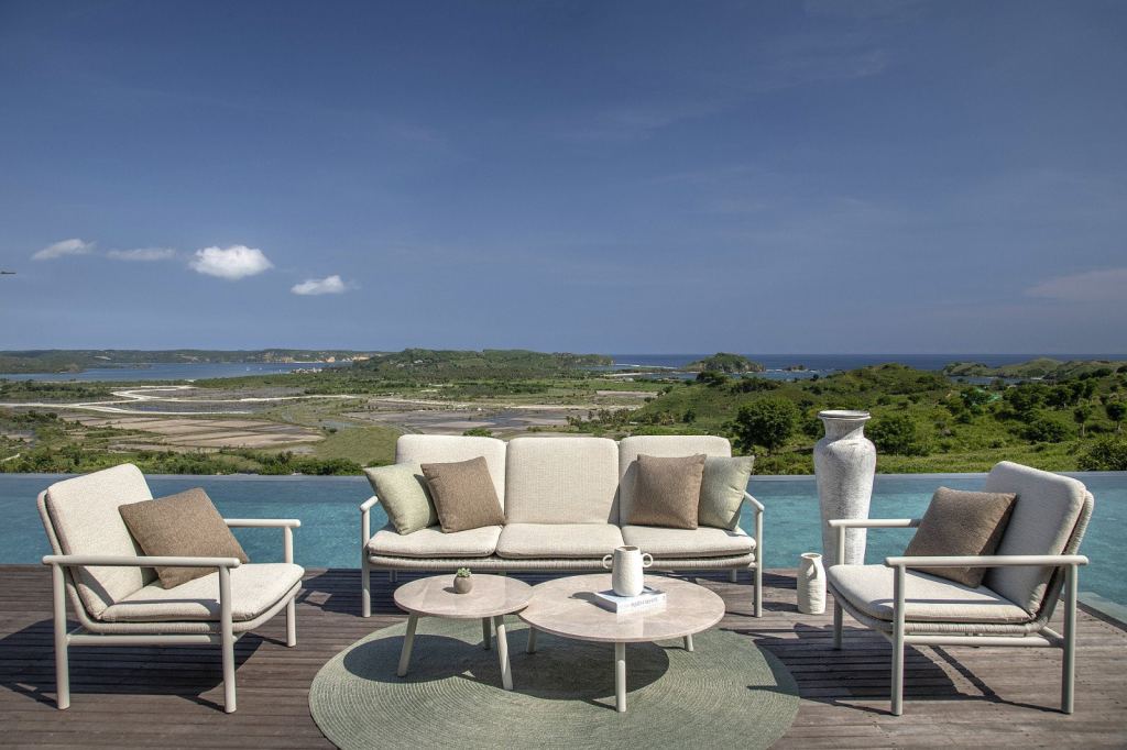 Moderne Gartenm&ouml;bel, zwei Sessel und ein Sofa mit Kissen, vor einer herrlichen Aussicht und einem Pool.