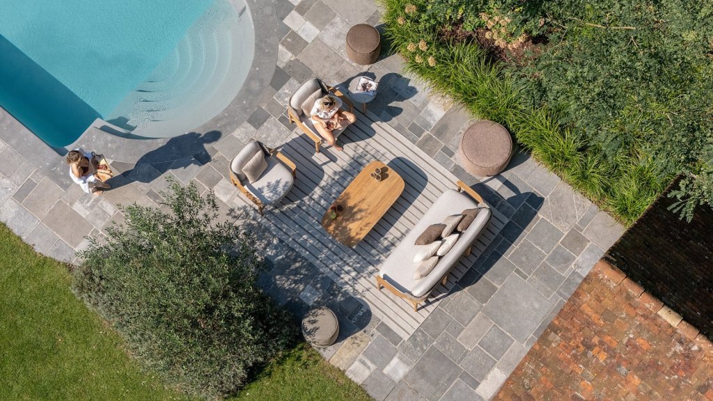 Ontspan in stijl met luxe tuinmeubels!. Moderne tuinmeubels rond een zwembad, met een houten tafel en comfortabele stoelen, ideaal voor ontspanning in de tuin.