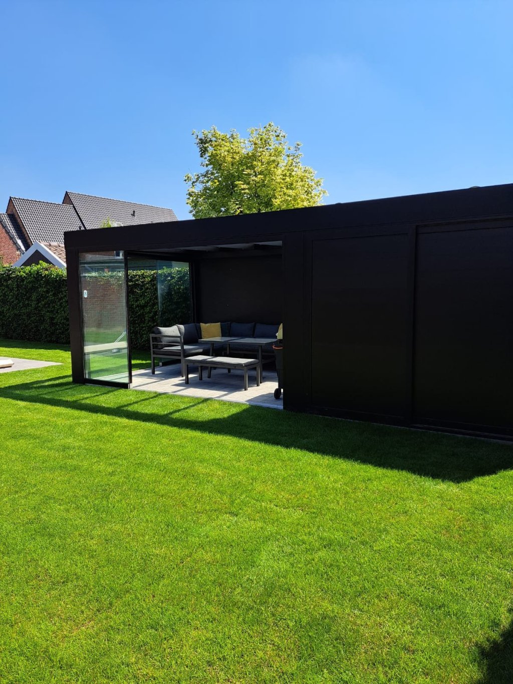 Glazen schuifwanden in Sittard - Geleen Limburg. Moderne overkapping met glazen schuifwanden en een gezellig zitgedeelte met perfecte grasmat.