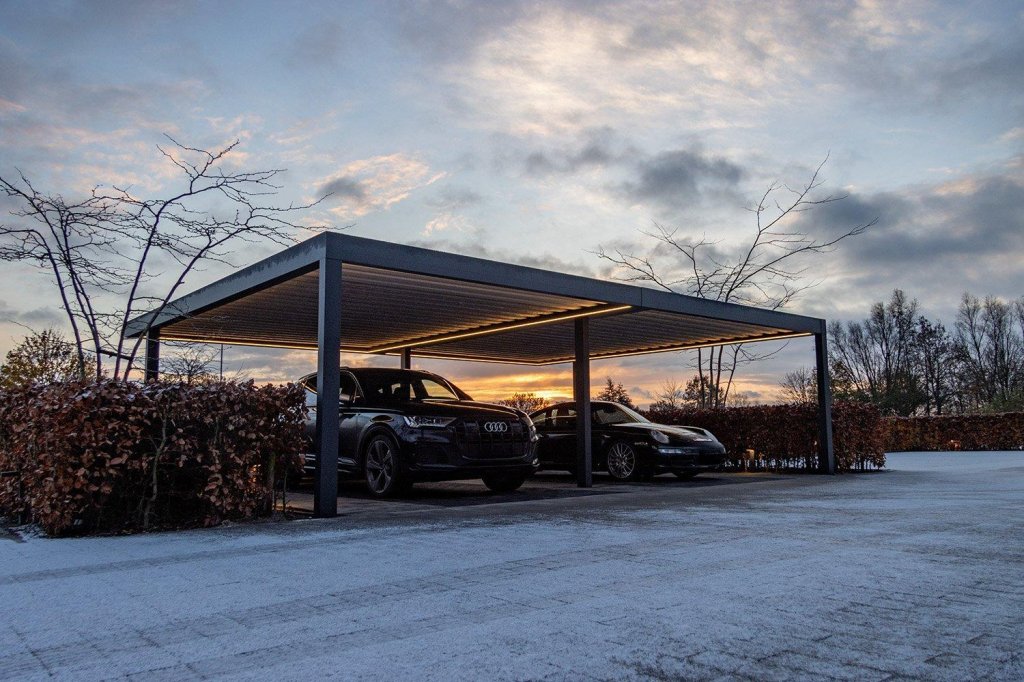Dubbele aluminium carport met LED-verlichting en twee auto's bij schemering.
