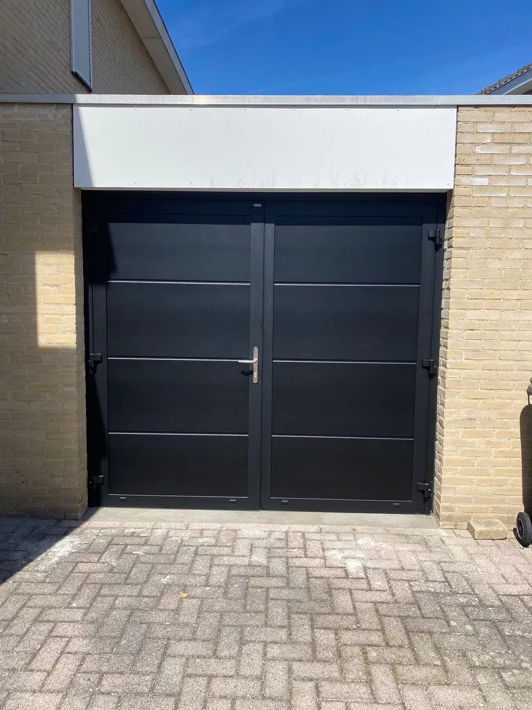 Moderne schwarze Flügeltore aus Aluminium mit Felderteilung, passgenau nach Maß in eine gemauerte Garage eingebaut, für eine geradlinige und zeitlose Optik.