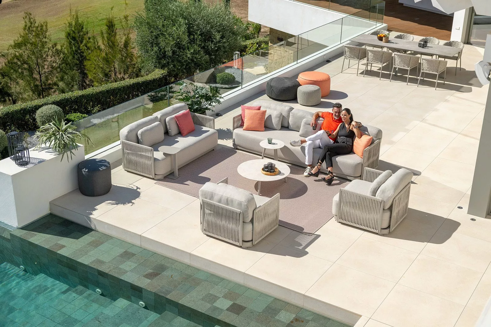 Moderne Gartenmöbel mit Lounge-Ecke und farbenfrohen Kissen auf einer Terrasse am Pool.