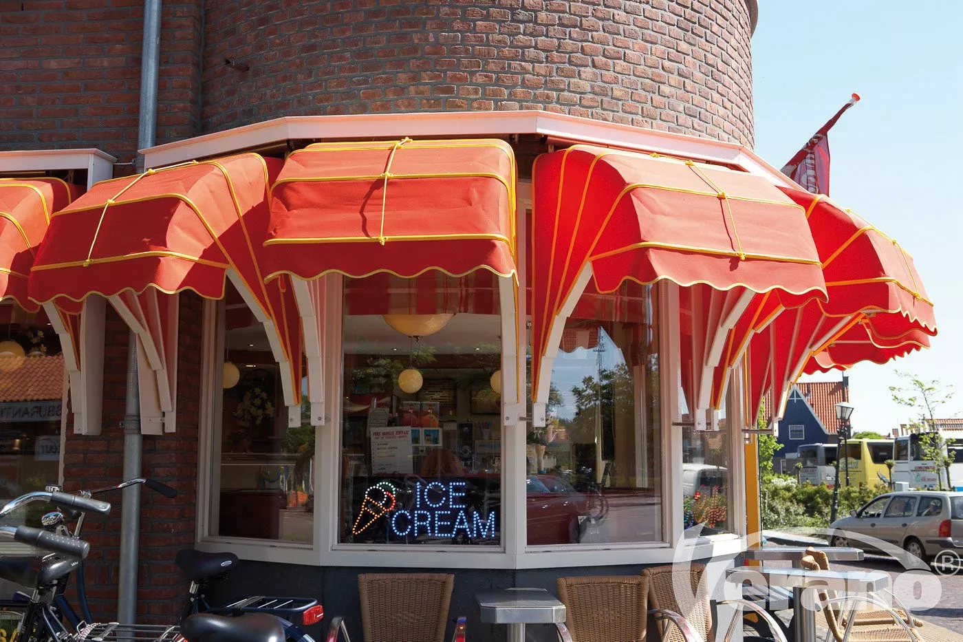 Ice-cream parlour fitted with Dutch canopies in a bold red with yellow accents, keeping the parlour pleasantly cool.