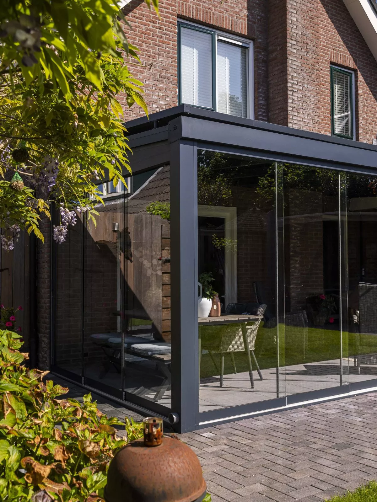 Stilvolle freistehende Überdachung mit Glaswänden, ideal im Garten eines modernen Hauses.