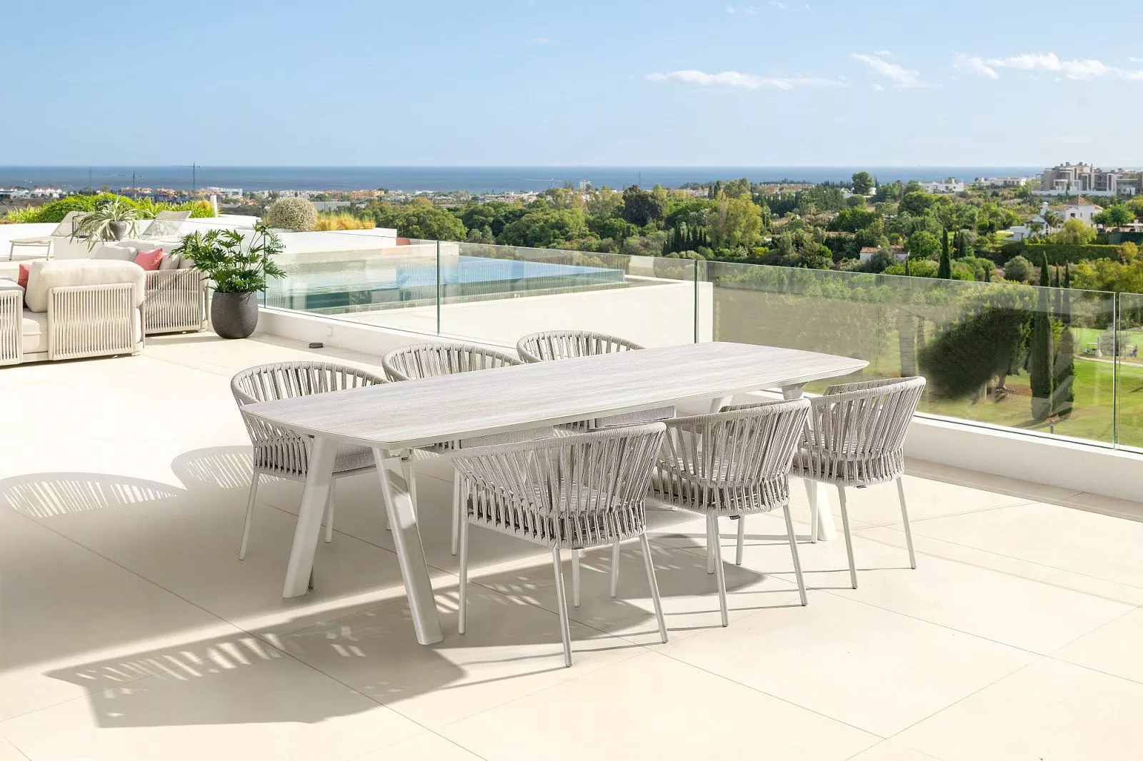 Modernes Gartenset mit langem Tisch und Stühlen aus Geflecht, ideal zum Essen im Freien.