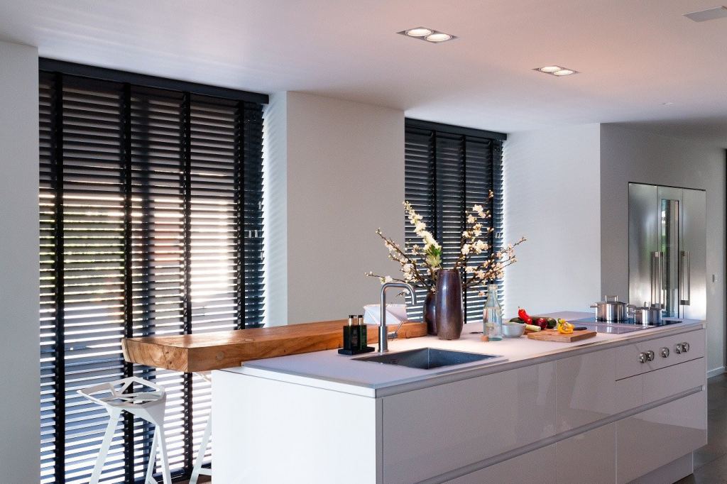 Sleek black venetian blinds dress the windows of a modern, stylish kitchen in Sittard-Geleen, Limburg.