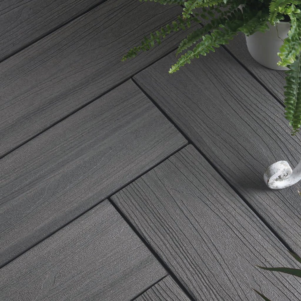 Composiet vlonderplanken Renoco Sittard - Geleen Limburg. Strakke, donkergrijze composiet vlonderplanken met natuurlijke houtlook en een plant in witte pot.