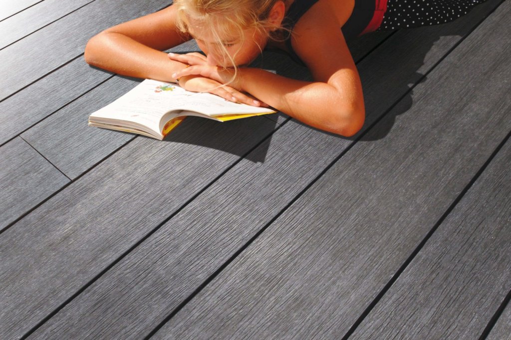 Composiet vlonderplanken in donkere kleur met een kind dat geniet van een boek.