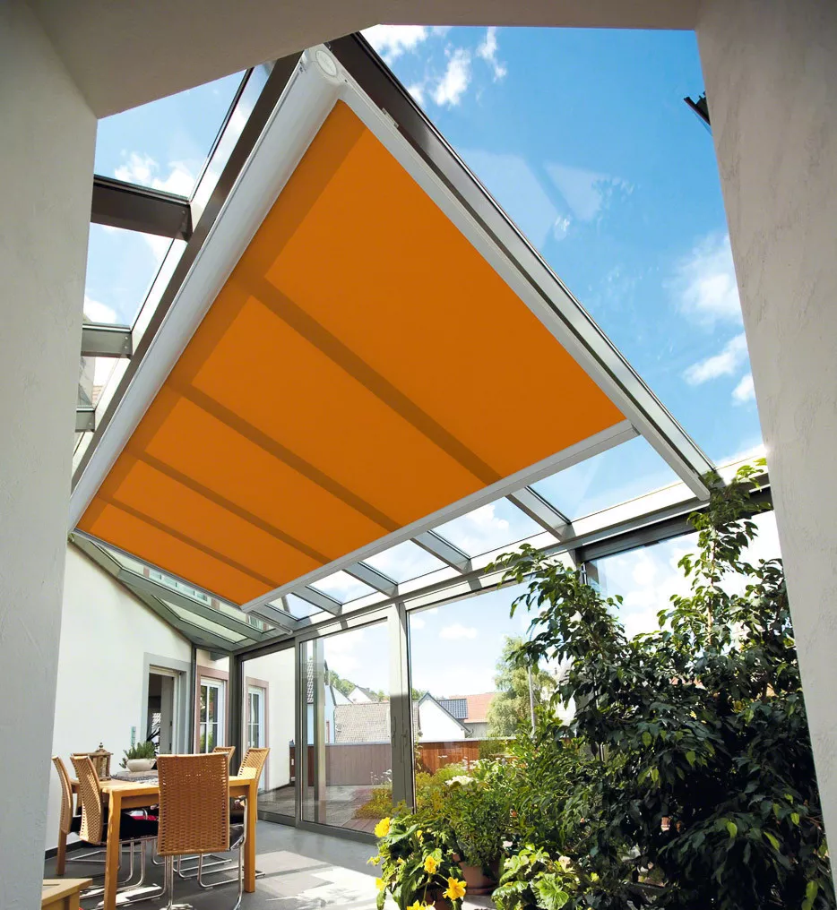 Glazen terrasoverkapping aan huis met oranje veranda zonwering met uitzicht op de tuin.