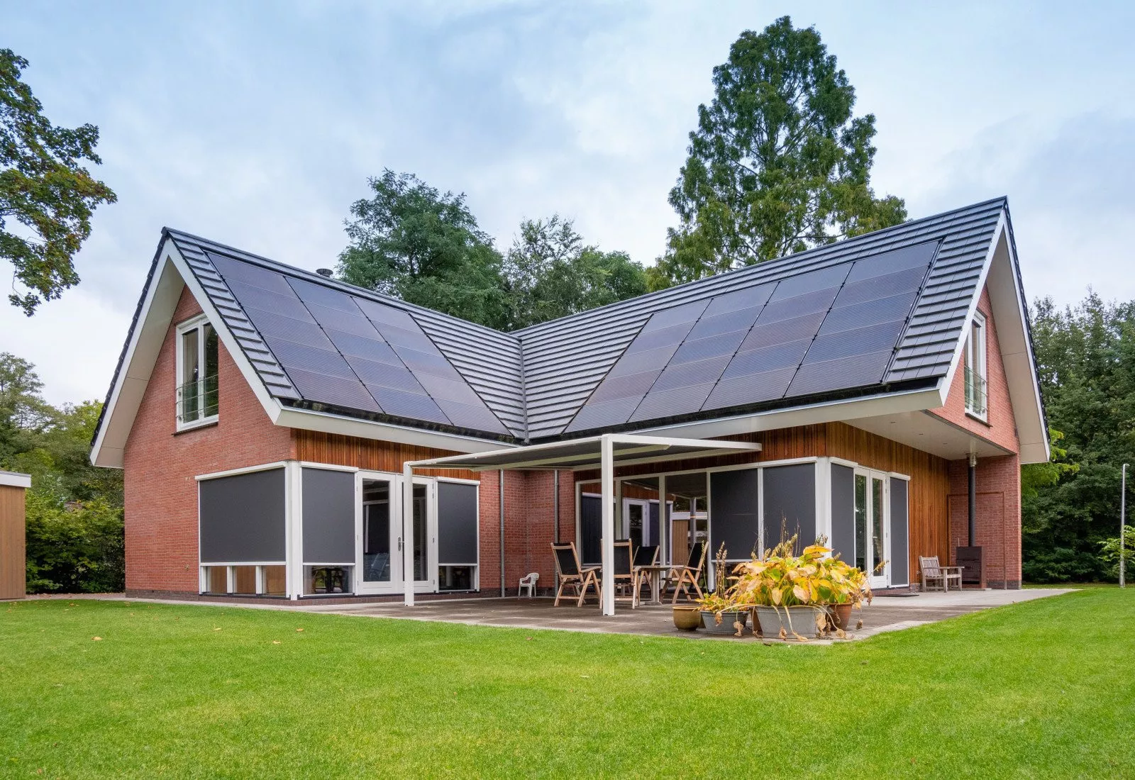 Großzügiges Haus mit Solarmodulen und Screens als Sonnenschutz an den Fenstern.