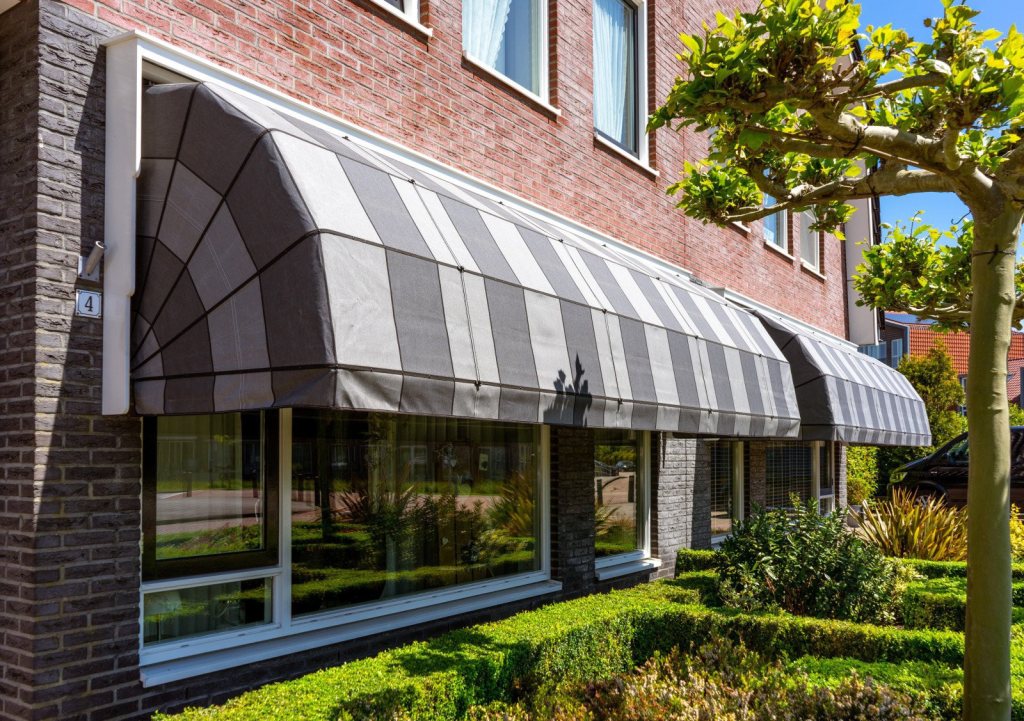 Grey-striped Dutch canopies fitted to a front fa&ccedil;ade provide protection from sun and heat.