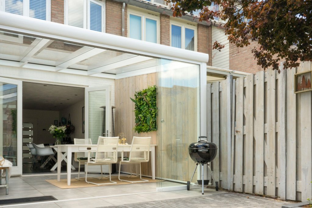 Chique veranda voor ultiem buitengenot in Sittard - Geleen of Limburg!. Strakke veranda met glazen wanden en modern tuinmeubilair aan een rijtjeswoning.