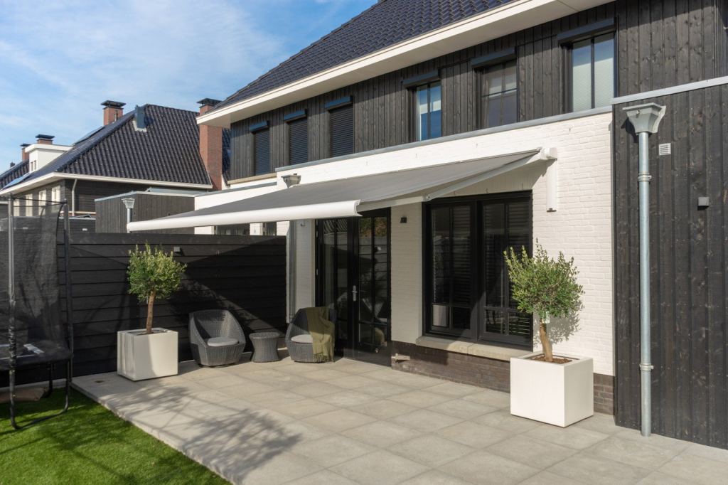 Grey folding-arm awning provides shade for your home, keeping it cool indoors.