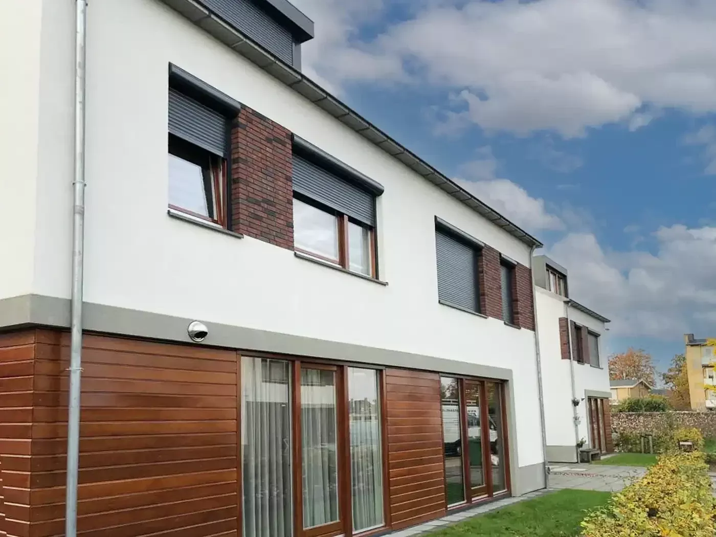 Manually operated roller shutters on a modern home with a timber and white façade.